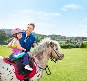 Ein Mann und ein Kind auf einem Pferd.