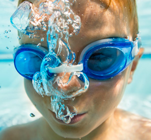 Ein Junge mit Taucherbrille unter Wasser.