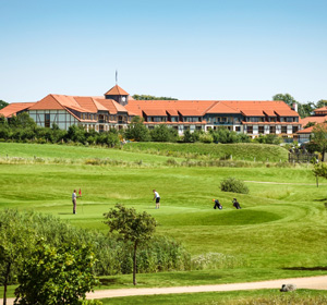 Blick auf grüne Wiese und in der Ferne gelegenes Hotel.